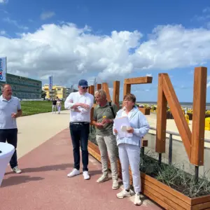 Menschengruppe vor dem Duhnen Schriftzug am Strand bei sonnigem Wetter.