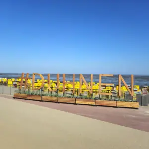 #DUHNEN Schriftzug aus Holz vor gelben Strandkörben am Nordseestrand.