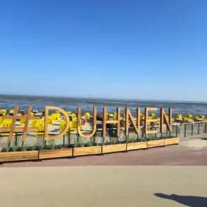Holzschriftzug #DUHNEN vor gelben Strandkörben am Strand von Cuxhaven.