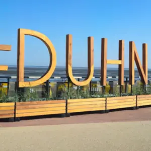 Großer hölzerner #DUHNEN Schriftzug an der Strandpromenade vor dem Meer.