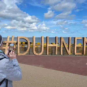 Person fotografiert hölzernen #DUHNEN-Schriftzug am Strand von Cuxhaven.