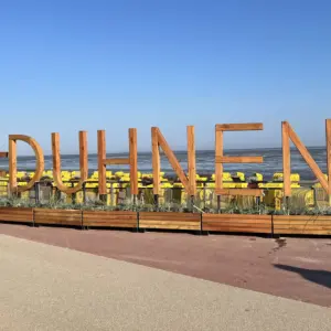 Hölzerner Schriftzug #DUHNEN an der Strandpromenade vor dem Wattenmeer.