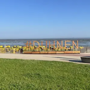 Holzschriftzug #DUHNEN vor gelben Strandkörben an der Nordsee.