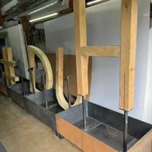 Große Holzbuchstaben montiert in Metallkästen in einer Werkstatt.