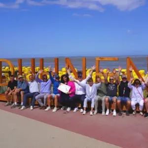 Gruppe winkt vor dem #DUHNEN Schriftzug am Strand.