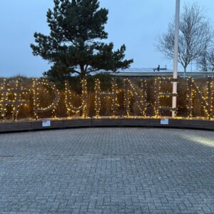 Beleuchteter Schriftzug #DUHNEN zwischen zwei geschmückten Weihnachtsbäumen.
