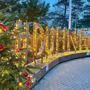 Beleuchteter Duhnen-Schriftzug mit geschmückten Weihnachtsbäumen bei Dämmerung.